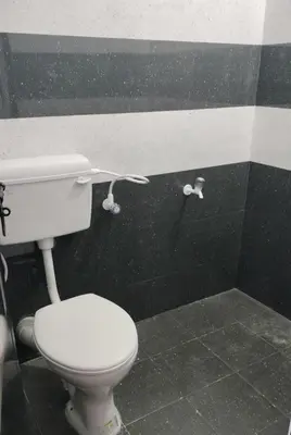 a bathroom with a white toilet in a black wall at Aswathy Bhavan Vadakkenchery Near Star auditorium in Vadakkāncheri