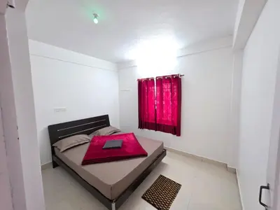 a bedroom with a bed with a red curtain at SRB Cottages in Ooty
