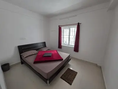 a bedroom with a bed with a red blanket on it at SRB Cottages in Ooty