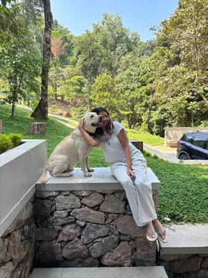 a woman sitting on a bench with a dog at Lucas Rainforest in Kakkabe