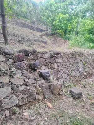 an old stone wall on the side of a hill at Maanasam Farmstay - Boutique 3BR Countryside Villa, Manikkadavu in Irrity