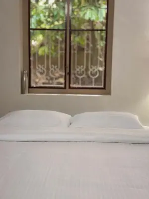 a white bed with a window in a bedroom at Maanasam Farmstay - Boutique 3BR Countryside Villa, Manikkadavu in Irrity