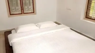two white beds in a room with two windows at Maanasam Farmstay - Boutique 3BR Countryside Villa, Manikkadavu in Irrity