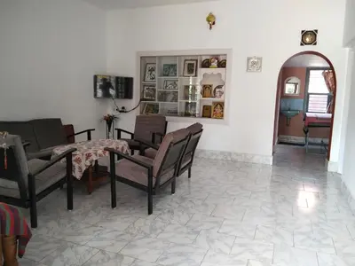 a living room with a table and chairs at Lakshmi Vasan Homestay in Madikeri
