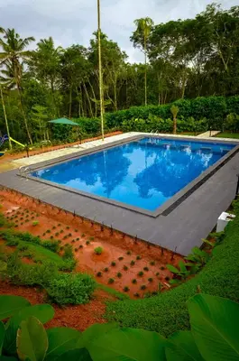 a large swimming pool with blue water in a yard at wayanadjunglevillas in Kenichira