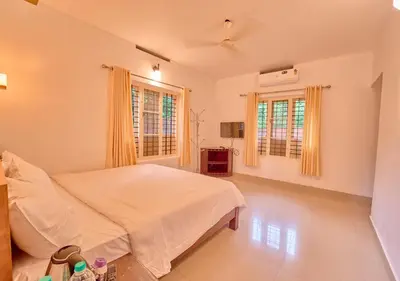 a bedroom with a bed and two windows at Kedara Resort Wayanad by VOYE HOMES - Pet Friendly with Pool in Sultan Bathery