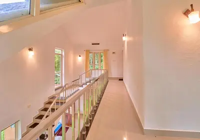 a staircase in a home with white walls and windows at Kedara Resort Wayanad by VOYE HOMES - Pet Friendly with Pool in Sultan Bathery