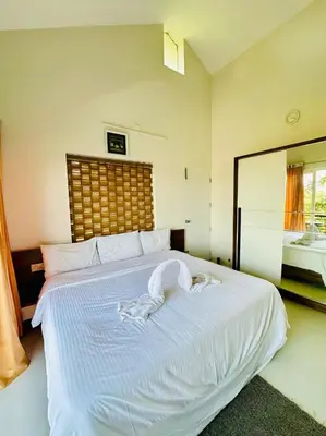 a bedroom with a bed with white sheets and a mirror at Zero Degree in Ketti
