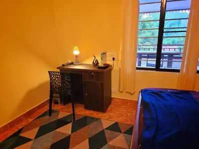 a room with a desk with a lamp and a window at Tranquil Nest Villa - Wayanad in Kalpetta