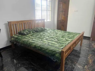 a wooden bed with a green comforter in a room at AC 3BHK Full House Kitchen strong WiFi Pollachi in Pollāchi