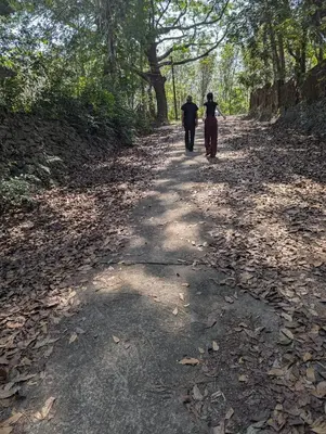 two people are walking down a dirt road at Ganesha Homestay, Cochin, Near Paniyeli Poru Waterfalls in Malayāttūr