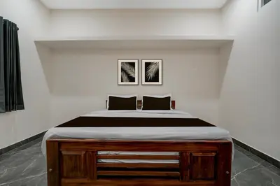 a bed in a white room with two pictures on the wall at Hotel O Ambari Residency in Mysore