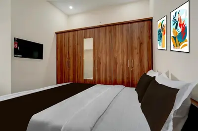 a bedroom with a large bed and a wooden door at Hotel O Ambari Residency in Mysore