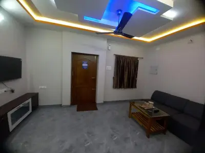 a living room with a couch and a tv at Maruthamalai Andavar Residency in Coimbatore