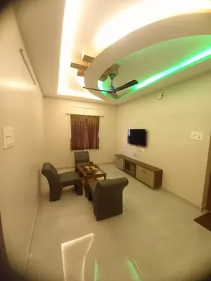 a living room with a couch and chairs and a tv at Maruthamalai Andavar Residency in Coimbatore