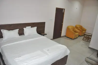 a bedroom with a large white bed and two chairs at Parvathi comforts inn in Mysore