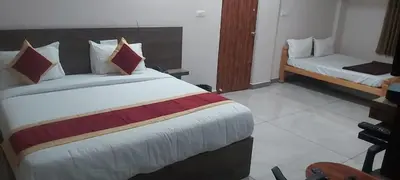 a hotel room with a large bed and a couch at Parvathi comforts inn in Mysore