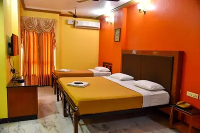 two beds in a room with orange walls at Hotel Grand Palace in Coimbatore