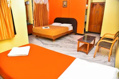 a bedroom with orange walls and a bed and a table at Hotel Grand Palace in Coimbatore