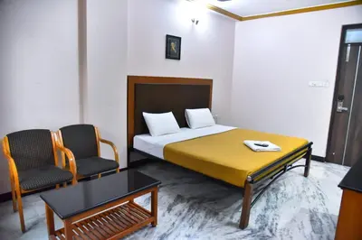 a bedroom with a bed and two chairs and a table at Hotel Grand Palace in Coimbatore