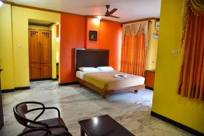 a bedroom with a bed with orange and yellow walls at Hotel Grand Palace in Coimbatore