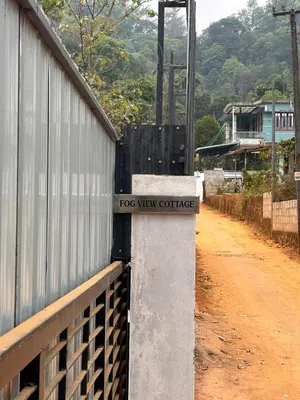 a sign on a wall next to a dirt road at Fog view cottage - Homestay with food and internet in Vythiri