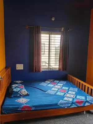 a bedroom with a bed with a blue wall and a window at love moon home stay in Mysore