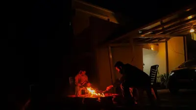 a woman and a child standing around a fire at Willostays Cluster Clouds in Ooty