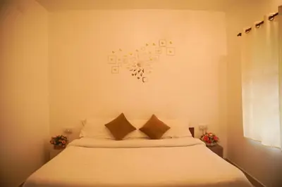a bedroom with a bed with white sheets and a clock on the wall at Willostays Cluster Clouds in Ooty