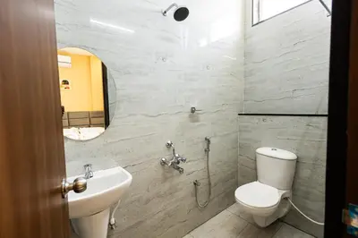 a bathroom with a toilet and a sink and a mirror at Sree Home Stay and Service Apartment Coimbatore in Irugūr