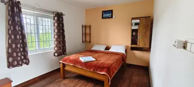 a small bedroom with a bed and a window at diamond hill view cottage in Ooty