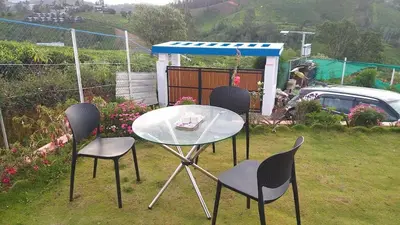 a glass table and chairs in a yard at diamond hill view cottage in Ooty