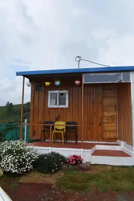 a wooden cabin with a table and a window at diamond hill view cottage in Ooty