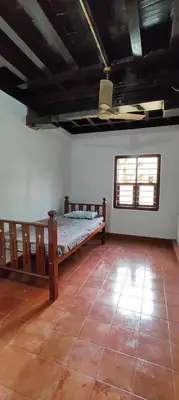 a room with a bed in the corner of a room at Traditional Kerala house, Kannur-Thalassery in Tellicherry