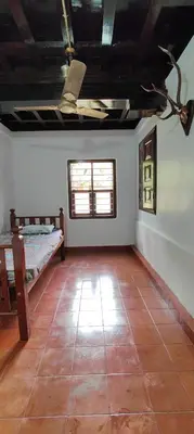 a room with a bed and a tiled floor at Traditional Kerala house, Kannur-Thalassery in Tellicherry