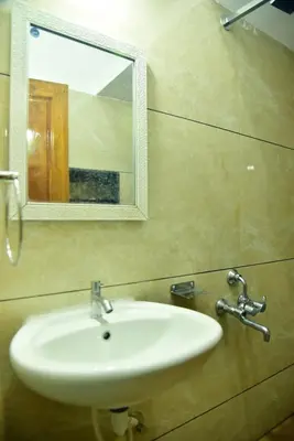 a white sink in a bathroom with a mirror at Mysuru Family Home Stay in Mysore