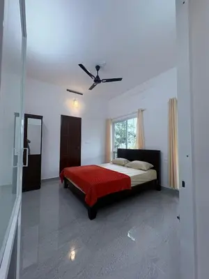 a bedroom with a bed and a ceiling fan at Eve's Residency in Meppādi