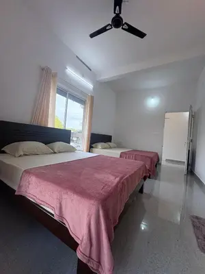 a bedroom with two beds and a ceiling fan at Eve's Residency in Meppādi