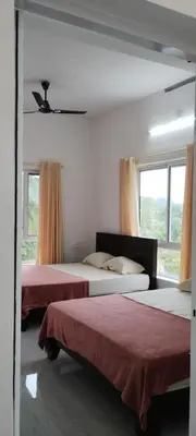 a bedroom with two beds and a window at Eve's Residency in Meppādi