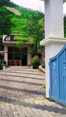 a house with a blue gate in front of it at Mamalakandam Green Hill Stay in Diya Homesay in Mamalakandam