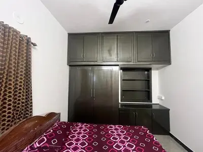 a kitchen with black cabinets and a red bed at AC 3BHK premium house in Pollāchi