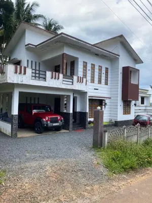 a white house with a red truck parked in front of it at Travango Settukunnu in Vythiri