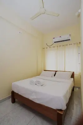 a bedroom with a white bed with a ceiling fan at Samruddhi Service Apartments in Mysore