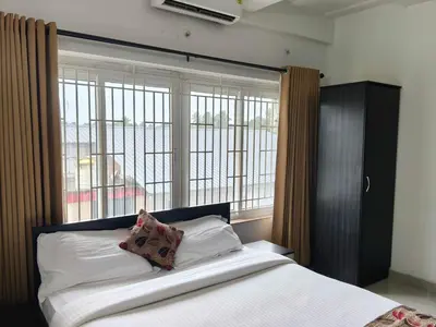 a bedroom with a bed with a large window at Townhouse Kozhikode Beach Formerly Point Avenue in Kozhikode