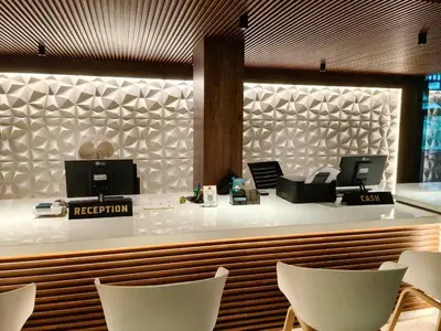 a restaurant with a reception counter with white chairs at Townhouse Kozhikode Beach Formerly Point Avenue in Kozhikode