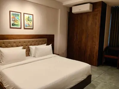 a bedroom with a white bed and a wooden cabinet at Townhouse Kozhikode Beach Formerly Point Avenue in Kozhikode