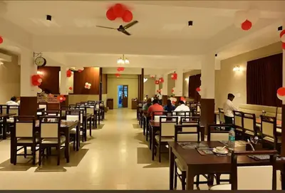 a dining room with tables and chairs and people eating at Ridhis Stay in Virajpet