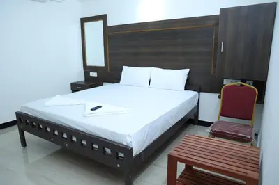 a bedroom with a bed with a mirror and a chair at Hotel Aranmanai in Coimbatore