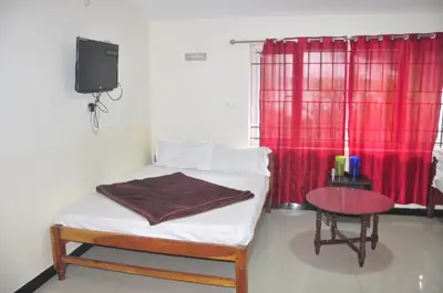 a bedroom with a bed with a table and a tv at HS Cottage Ooty in Ooty