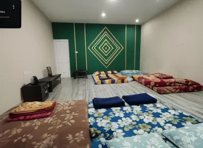 two beds in a room with green walls at Hanni Resort in Kotagiri